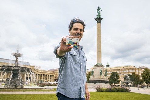 Mann steht auf dem Stuttgarter Schloßplatz und hält die ErlebnisCard in der Hand