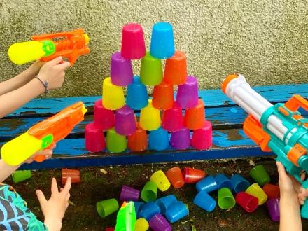 Foto: Michael Mikolajczak Kinderhände halten Wasserpistolen auf Plastikbecher