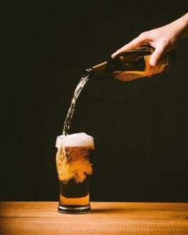 Aus einer Flasche wird Bier in ein Glas eingeschenkt
