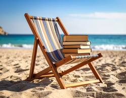 Ein Stapel Bücher liegt auf einem Liegestuhl am Strand, dahinter das Meer.