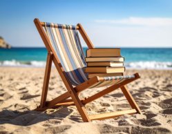 Klappliegestuhl am Strand mit einem Stapel Bücher darauf