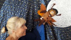 Schauspielerin hält vor Sternenkulisse Figur Herrn Sumsemann in die Höhe.